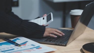 Genç iş kadını ofiste dizüstü bilgisayar ve akıllı telefonla çalışıyor..