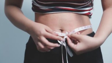 Bel ölçüsü ile belini ölçen kadın.