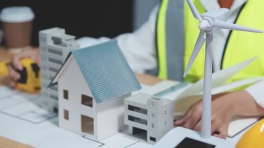 mühendis ya da mimar ya da mühendis ev modeli üzerinde planlar, planlar ve inşaat alanı konseptiyle çalışıyor.
