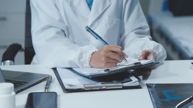 Doktor ofisteki masada bir panoya yazı yazıyor..