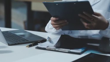 Hastane ofisinde dizüstü bilgisayarda çalışan erkek doktor.