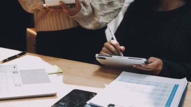 Ofiste çalışırken cep telefonu kullanan genç bir kadın.