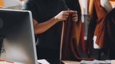 Moda tasarımcısı stüdyoda dizüstü bilgisayarda çalışıyor.