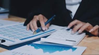 İş adamı hesap makinesi ve dizüstü bilgisayarla finansal tabloları analiz ediyor