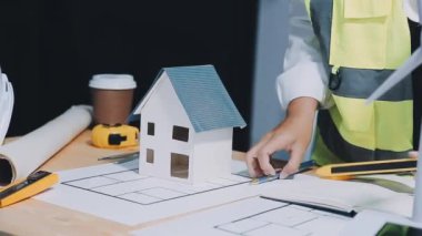 Mimar üniformalı genç bir kadın planlarla çalışıyor.