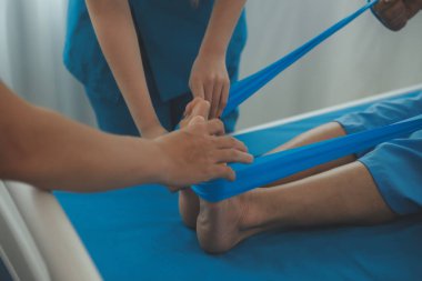 Klinikteki küçük hastanın bacağını muayene eden profesyonel bir ortopedist. Fizyoterapideki hasta terapistiyle fiziksel egzersiz yapıyor.