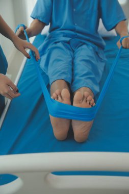 Klinikteki küçük hastanın bacağını muayene eden profesyonel bir ortopedist. Fizyoterapideki hasta terapistiyle fiziksel egzersiz yapıyor.