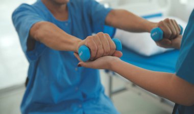 Egzersiz halter tedavi hakkında kol ve omuz sporcu ile erkek hastanın fizik tedavi kavramı veren fizyoterapist adam