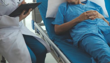 Doktor nabzını kontrol ederken hastanede yatan bir adam. Kadın doktor, erkek hastayı hastane odasında muayene ediyor..