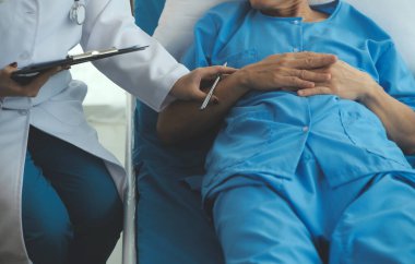 Doktor nabzını kontrol ederken hastanede yatan bir adam. Kadın doktor, erkek hastayı hastane odasında muayene ediyor..