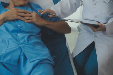 Doktor nabzını kontrol ederken hastanede yatan bir adam. Kadın doktor, erkek hastayı hastane odasında muayene ediyor..