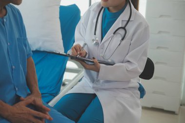 Genç bayan doktor ve hemşireler hastanede konsültasyon yapan yaşlı ve mutlu erkek hastalarla konuşmaya yardım ediyorlar. Değer veren, cesaretlendiren ve olgun erkekleri rahatlatan. sağlık hizmeti kavramı