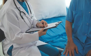 Genç bayan doktor ve hemşireler hastanede konsültasyon yapan yaşlı ve mutlu erkek hastalarla konuşmaya yardım ediyorlar. Değer veren, cesaretlendiren ve olgun erkekleri rahatlatan. sağlık hizmeti kavramı