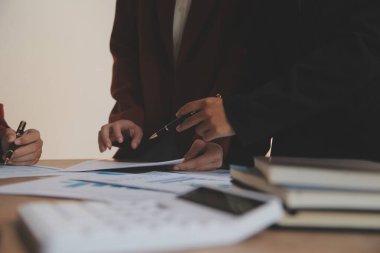 Group of confident business people point to graphs and charts to analyze market data, balance sheet, account, net profit to plan new sales strategies to increase production capacity.