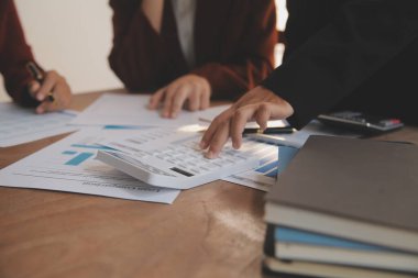 Group of confident business people point to graphs and charts to analyze market data, balance sheet, account, net profit to plan new sales strategies to increase production capacity.