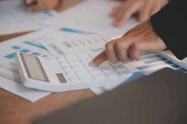 Group of confident business people point to graphs and charts to analyze market data, balance sheet, account, net profit to plan new sales strategies to increase production capacity.