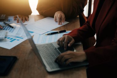 Group of confident business people point to graphs and charts to analyze market data, balance sheet, account, net profit to plan new sales strategies to increase production capacity.