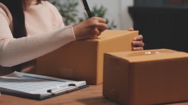 Asyalı kadın çevrimiçi teslimat servisinde kutuları paketliyor. Müşteri hizmetleri ve çevrimiçi dağıtım hizmeti.