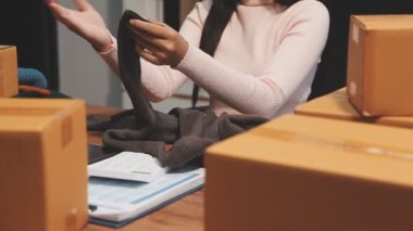 Asyalı kadın evdeki ofisinde paket kutusu paketliyor..