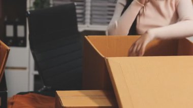 Genç bir kadın eve taşınmak için kutuları karton bir kutuya koyuyor..