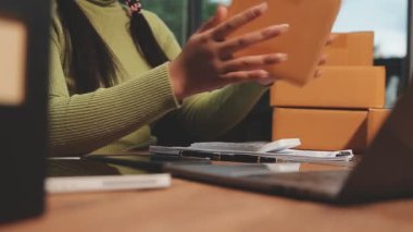 Ofisinde dizüstü bilgisayarı olan akıllı telefon kullanan kadın.