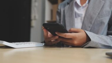 Adam akıllı telefonu tutuyor ve kafede dizüstü bilgisayar kullanıyor.