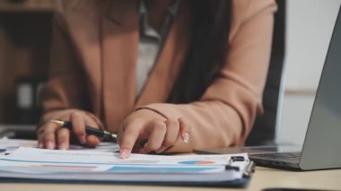 Beyaz gömlekli, siyah takım elbiseli, dizüstü bilgisayarı ve masada belgeleri olan genç bir kadın mimar.