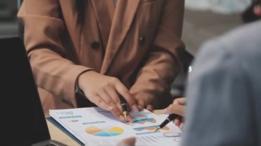 Genç iş kadını elinde bir kalemle mali planı tartışıyor.