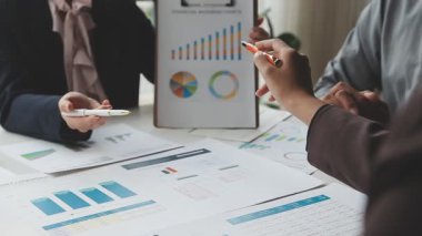 Bir grup iş arkadaşı iş planını tartışıyor ve ofiste verileri analiz ediyorlar..