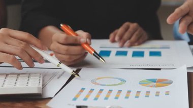 İş adamının mali raporunu hesap makinesi ve modern ofis masası ile ahşap masa üzerindeki kalemle gösteren el görüşünü kapat.