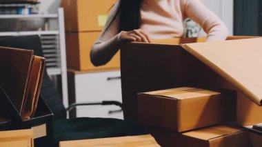 Karton kutuları depoya teslim etmek için paketleyen bir kadın.