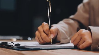 Yakın plan - modern ofisteki işyerindeki not defterine kalem yazan işadamlarının görüntüsü.