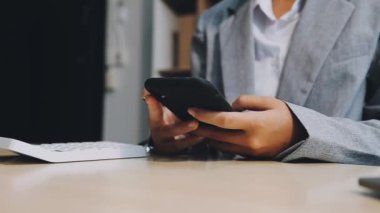 Genç Asyalı iş adamı akıllı telefon kullanıyor ve modern ofiste çalışıyor.