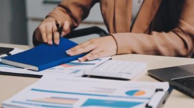 Masada finansal rapor ve dizüstü bilgisayarla çalışan genç Asyalı iş kadını..