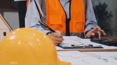 Kask ve koruyucu giysili genç mühendis ofiste çalışıyor.