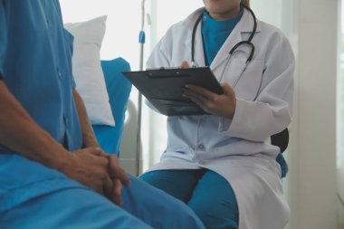 Genç bayan doktor ve hemşireler hastanede konsültasyon yapan yaşlı ve mutlu erkek hastalarla konuşmaya yardım ediyorlar. Değer veren, cesaretlendiren ve olgun erkekleri rahatlatan. sağlık hizmeti kavramı