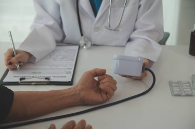 Steteskopla sfenometre kullanan bir doktor hastanede kan basıncını ölçüyor..
