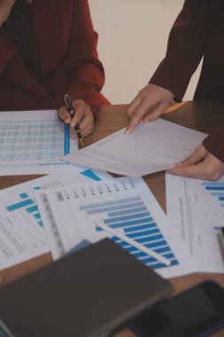 Group of confident business people point to graphs and charts to analyze market data, balance sheet, account, net profit to plan new sales strategies to increase production capacity.