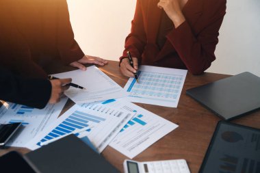 Group of confident business people point to graphs and charts to analyze market data, balance sheet, account, net profit to plan new sales strategies to increase production capacity.