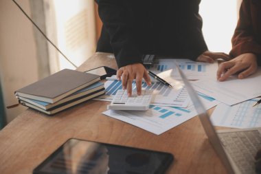 Group of confident business people point to graphs and charts to analyze market data, balance sheet, account, net profit to plan new sales strategies to increase production capacity.