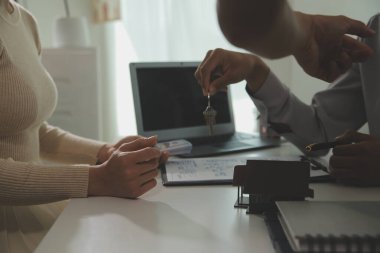 Emlakçı emlakçı ev modelini işaret eden bir kalem kullanıyor ve iş sözleşmesini, kirayı, satın almayı, ipoteği, krediyi veya ev sigortasını açıklıyor