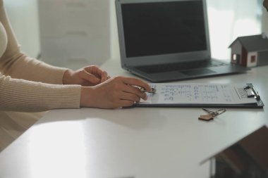 Emlakçı emlakçı ev modelini işaret eden bir kalem kullanıyor ve iş sözleşmesini, kirayı, satın almayı, ipoteği, krediyi veya ev sigortasını açıklıyor
