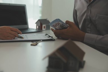 Emlakçı emlakçı ev modelini işaret eden bir kalem kullanıyor ve iş sözleşmesini, kirayı, satın almayı, ipoteği, krediyi veya ev sigortasını açıklıyor