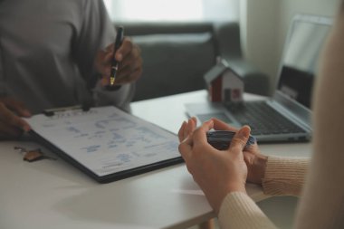 Emlakçı emlakçı ev modelini işaret eden bir kalem kullanıyor ve iş sözleşmesini, kirayı, satın almayı, ipoteği, krediyi veya ev sigortasını açıklıyor