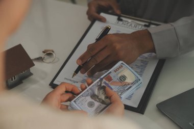 Emlakçı emlakçı ev modelini işaret eden bir kalem kullanıyor ve iş sözleşmesini, kirayı, satın almayı, ipoteği, krediyi veya ev sigortasını açıklıyor