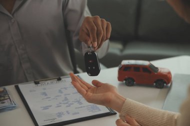 Genç bir adam araba satıcısından bir anahtar alır. Atölye, kredi kartı, sigorta, satış, araba satın alma ve finans konseptinde bir arabanın kirası veya satışı için anlaşma yaptıktan sonra.