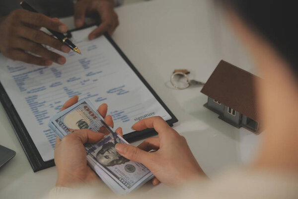 Real estate agent home sales broker is using a pen pointing to the house model and explains the business contract, rent, buy, mortgage, loan, or home insurance