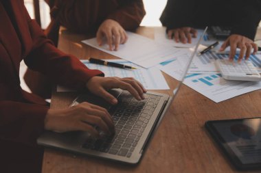 Group of confident business people point to graphs and charts to analyze market data, balance sheet, account, net profit to plan new sales strategies to increase production capacity.