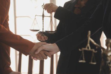 Avukat, müvekkil ile evraklar, sözleşmeler, anlaşmalar, iş birliği anlaşmaları hakkında el sıkışıyor avukatın masasında bir kadın müvekkil ve masada bir çekiç.