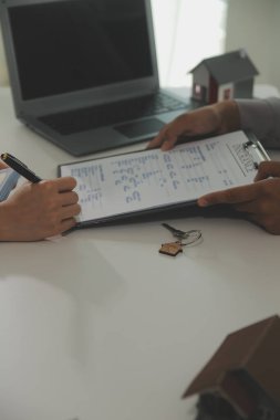 Emlakçı emlakçı ev modelini işaret eden bir kalem kullanıyor ve iş sözleşmesini, kirayı, satın almayı, ipoteği, krediyi veya ev sigortasını açıklıyor